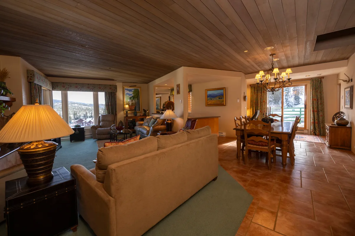 A stylish open living area featuring a comfortable seating area and a dining table, with large windows that look out onto stunning mountain scenery. The space is perfect for family gatherings, entertaining guests, or simply relaxing and enjoying the view.