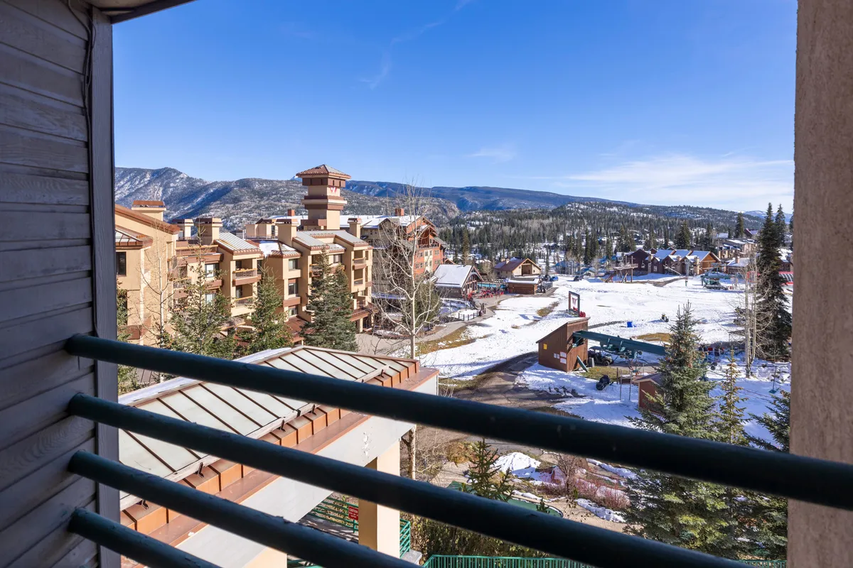 This image captures a snow-covered landscape with a dramatic mountain range in the background, dotted with residential buildings and pine trees. The tranquil setting hints at both outdoor adventures and moments of relaxation, making it a perfect backdrop for group getaways.