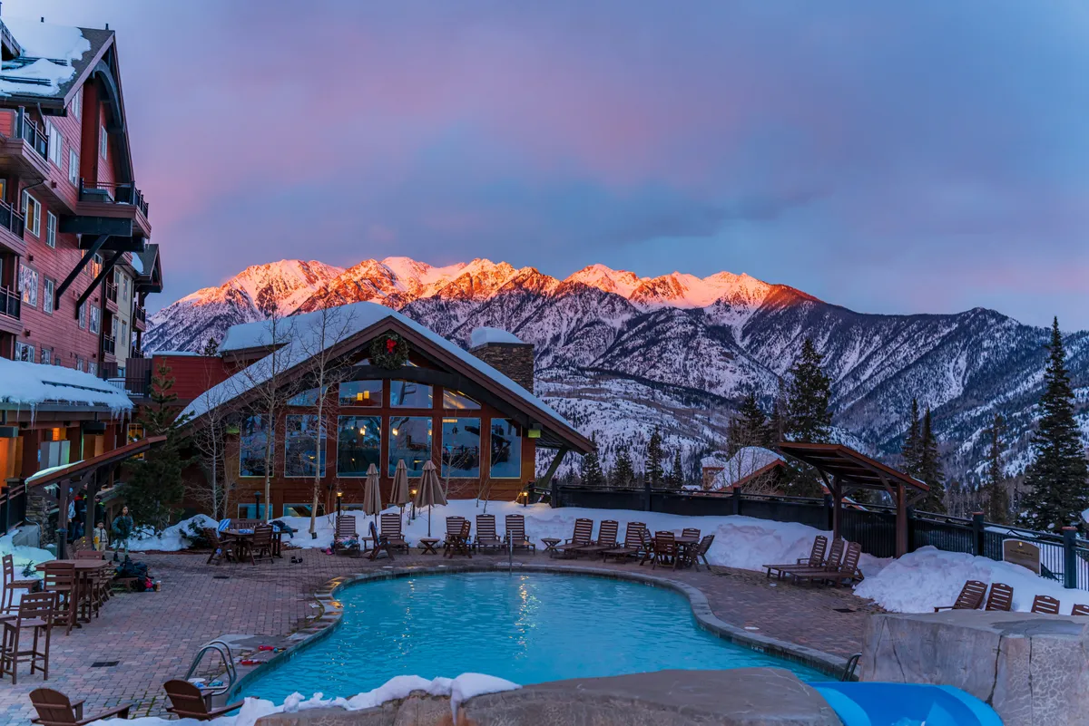 An inviting outdoor pool area overlooks the mountains, with a lodge and seating area nearby. The space is perfect for socializing, sunset viewing, and stargazing—echoing group-friendly moments described in the section.